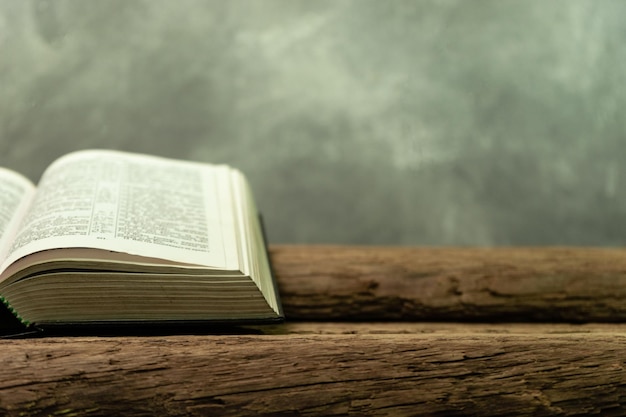 Bible ouverte et bougie sur une vieille table en bois de chêne Bel fond orange Concept religieux