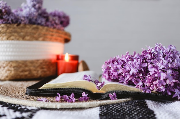 Une Bible ouverte avec une branche de lilas un panier en osier et une bougie sur la table Belle image esthétique bonjour