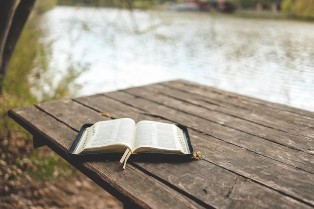 Photo bible ouverte sur une planche de bois près de la rivière