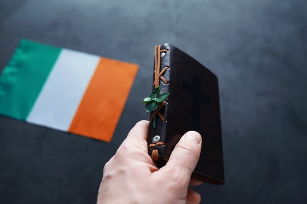 Une Bible reliée en cuir sur la table. Célébration religieuse chrétienne irlandaise. Trèfle à quatre feuilles symbole de bonne chance.