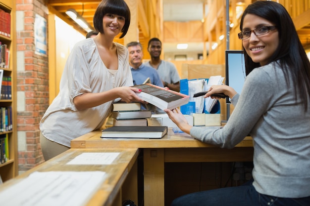 Bibliothécaire scanner un livre et le remettre à une femme