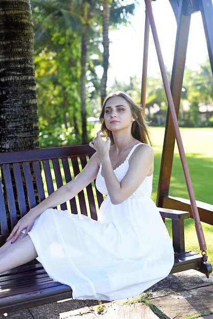 Biélorussie femme en robe blanche assise sur des balançoires en bois