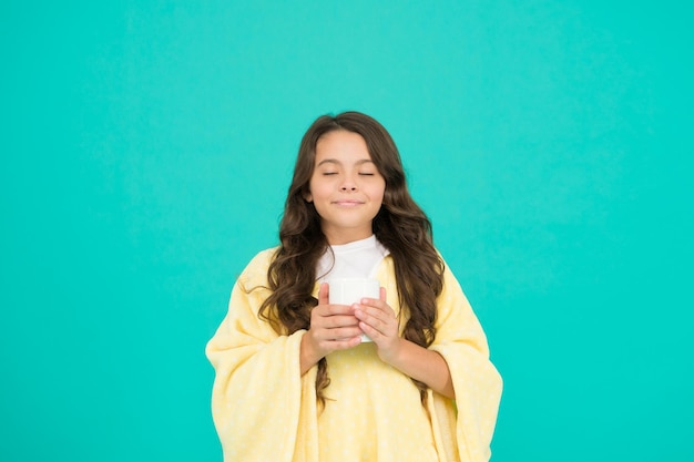 Bien boire bien vivre petite fille boire du cacao ou du lait avant de dormir pyjama confortable et moelleux se sentir à l'aise à la maison fille heureuse avec une tasse de thé bonjour boire petit enfant fond bleu