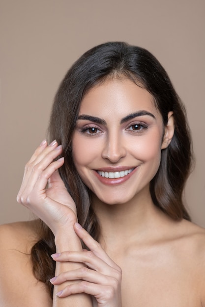 Bien-être. Beau Visage De Jeune Femme Brune Souriante Et Ses Fines Mains Gracieuses Avec Manucure