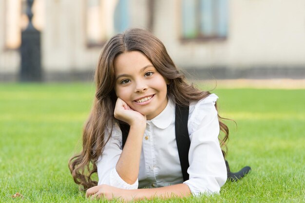 Bien-être mental Uniforme scolaire pour fille profiter de la détente Importance de la relaxation Petite écolière Se détendre dans la cour de l'école Enfant se détendre à l'extérieur Pause scolaire pour se reposer Adorable élève Fille enfant portant la pelouse