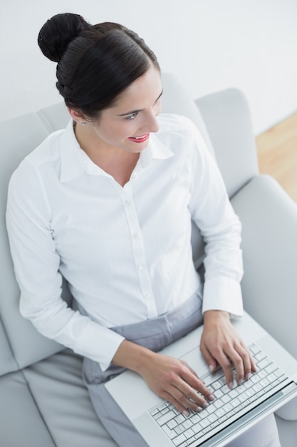 Bien habillée jeune femme utilisant un ordinateur portable sur le canapé