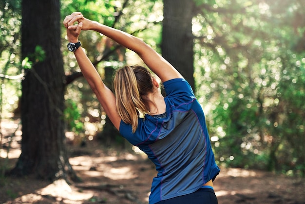 Bien s'étirer avant sa course Photo d'une jeune femme s'échauffant pour une course de trail