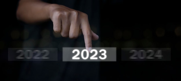 Bienvenue année 2023 Main d'homme d'affaires appuyant sur le bouton Nouvel An 2023 sur écran virtuel