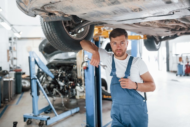 Bienvenue dans notre garage. L'employé en uniforme de couleur bleue travaille dans le salon automobile.