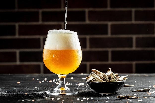 Bière artisanale versez de la bière dans un grand verre avec une mousse épaisse avec des collations gastronomiques pour la place des éclaboussures de bière pour le texte