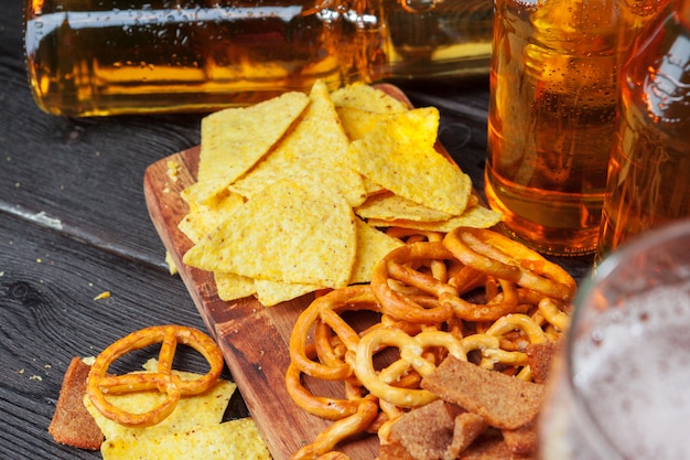 Bière blonde et des collations sur une table en bois. Noix, chips, bretzel