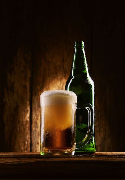 Bière avec une bouteille dans une tasse sur une table en bois