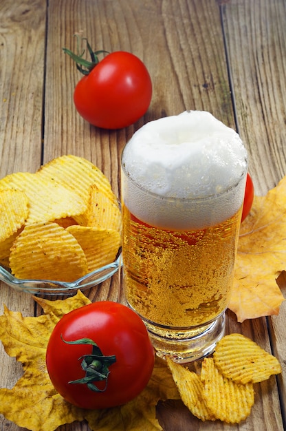 Bière, chips et tomates sur table en bois