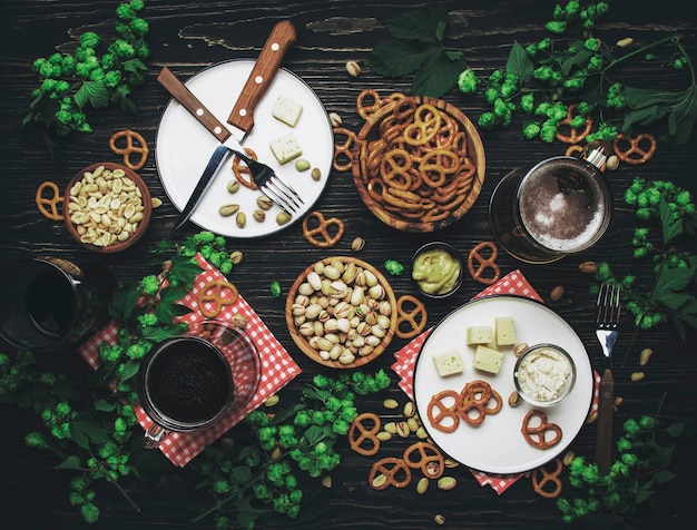 Bière claire et foncée dans des tasses et des collations salées et des noix cadre de table en bois foncé avec dessus d'espace de copie