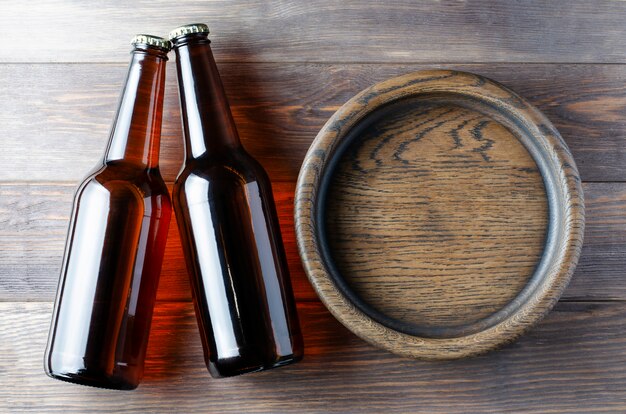 Bière dans des bouteilles en verre et une assiette en bois pour les collations. Fond en bois marron.