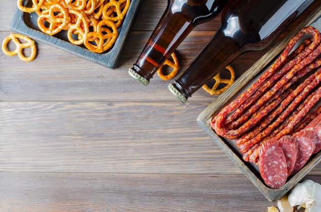 Bière dans des bouteilles en verre foncé, collations salées pour bière, saucisse