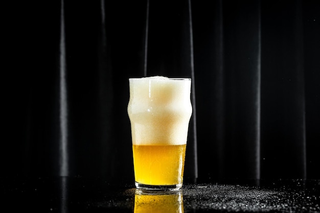 Bière dans un grand verre avec une mousse épaisse sur fond sombre Concept de brasserie de bière Collation pour la bière éperlans séchés Fond de bière