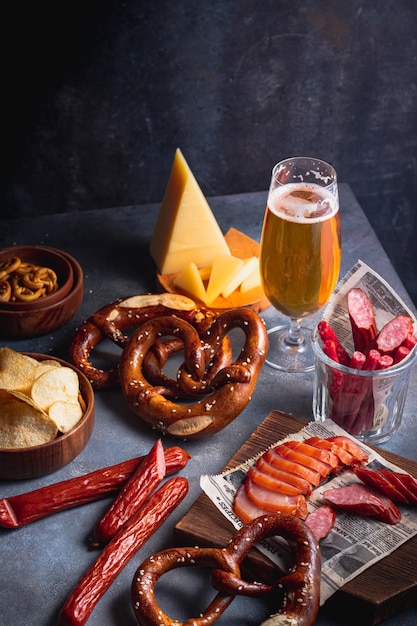 Bière dans le verre avec assortiment de collations à la bière brezel, fromage, croustilles, saucisses