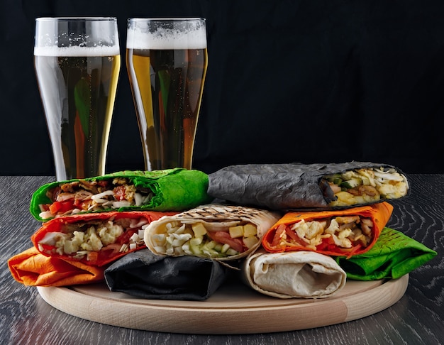 La bière dans un verre et le shawarma dans du pain pita sont coupés et reposent sur une surface en bois