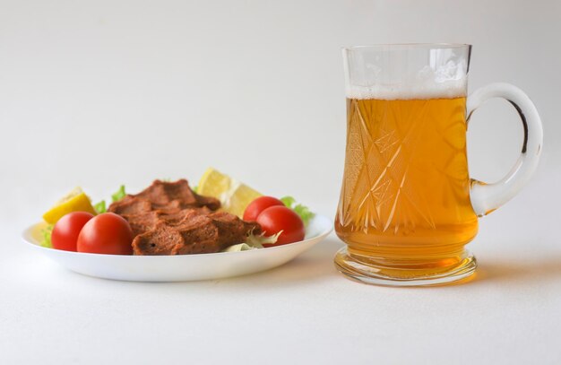 Bière sur fond blanc. Chope à bière froide en verre congelé. Boulettes de viande crues d'apéritif turc.