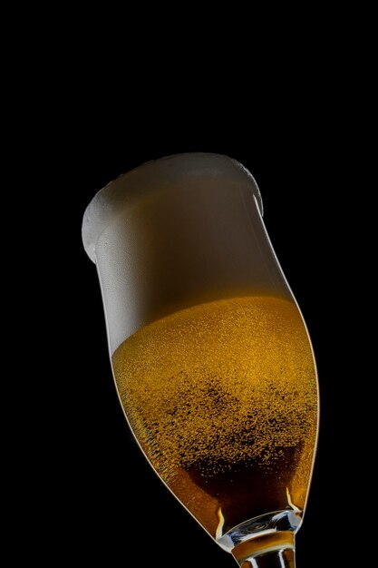 Bière fraîche dans un verre sur fond noir. Le concept de nourriture.