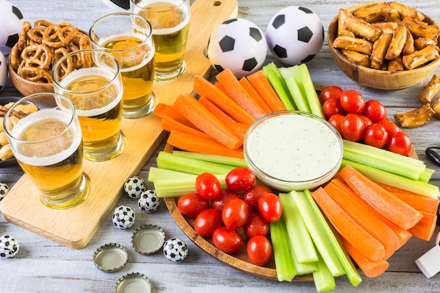 Bière pression et collations salées sur la table pour une fête de football.