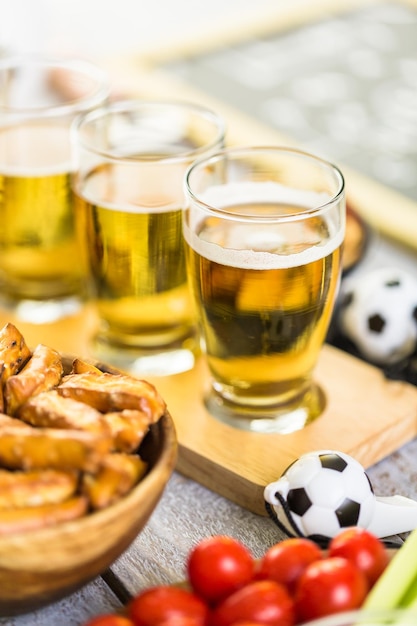 Bière pression et collations salées sur la table pour une fête de football.