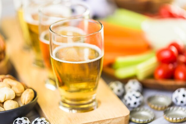 Bière pression et collations salées sur la table pour une fête de football.