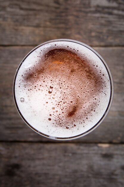 Bière en verre. Mousse de bière. Vue d'en haut sur une table en bois sombre