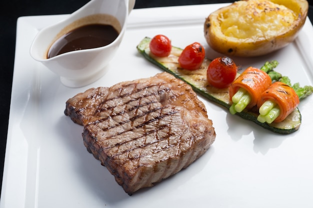 Photo bifteck de bœuf hida avec tomates grillées, carottes, concombres et asperges sur une plaque blanche