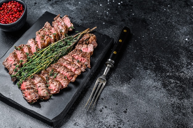 Bifteck de bœuf à la viande grillée à la machette. Fond noir. Vue de dessus. Copiez l'espace.