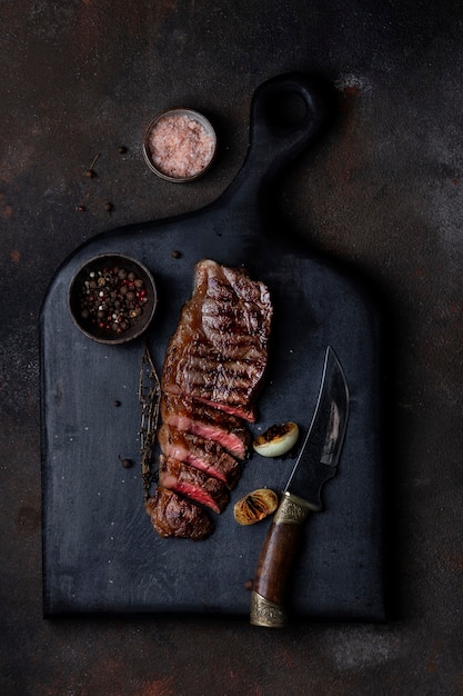 Bifteck de contre-filet de bœuf grillé en tranches au thym sur une planche de bois