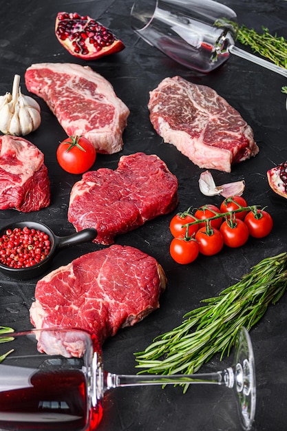 Bifteck de croupe de bœuf coupé devant le steak de lame supérieur avec assaisonnement aux herbes et verre de vin rouge sur la vue latérale du tableau noir