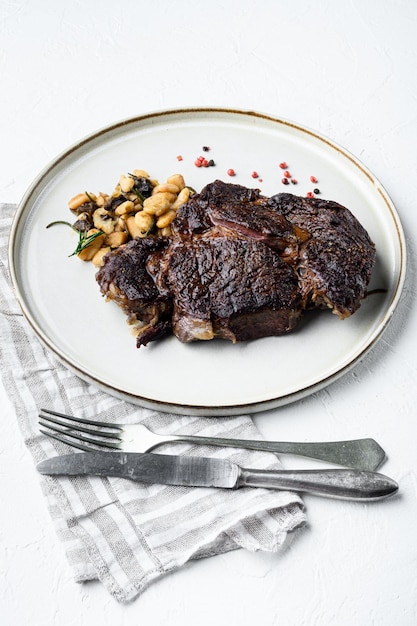 Bifteck de faux-filet aux herbes, haricots rôtis, thym et ail sur une surface en pierre blanche