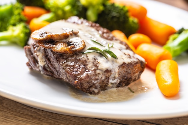 Bifteck de faux-filet de bœuf juteux avec sauce aux champignons et petits légumes.