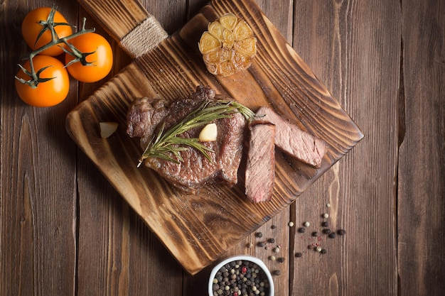 Bifteck de faux-filet grillé mi-saignant sur une planche de service en bois sur fond de table en bois