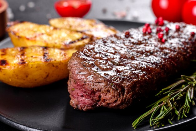 Bifteck de faux-filet avec pommes de terre, oignons et tomates cerises. Steak juteux au beurre aromatisé