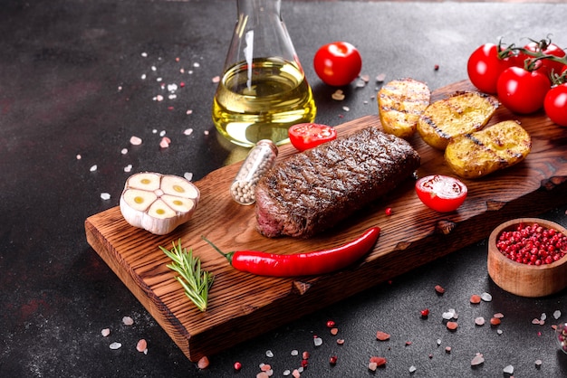 Bifteck de faux-filet avec pommes de terre, oignons et tomates cerises. Steak juteux au beurre aromatisé