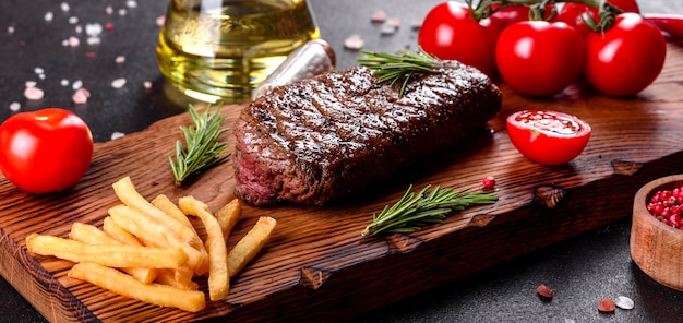 Bifteck de faux-filet avec pommes de terre, oignons et tomates cerises. Steak juteux au beurre aromatisé