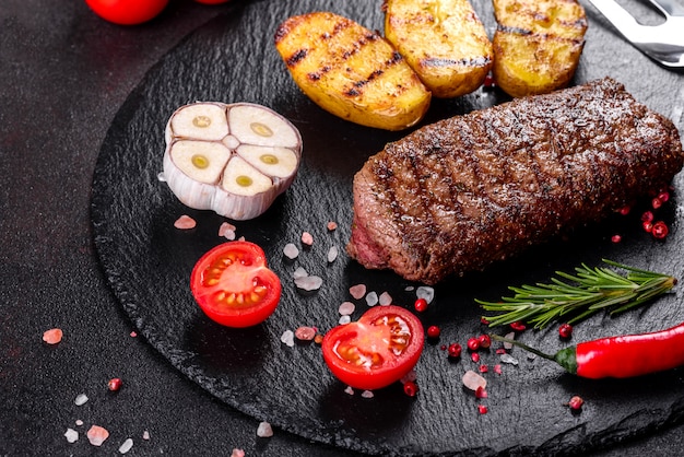 Bifteck de faux-filet avec pommes de terre, oignons et tomates cerises. Steak juteux au beurre aromatisé