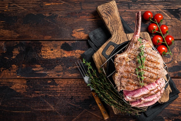 Bifteck de faux-filet de Tomahawk grillé sur le gril avec des herbes Fond en bois Vue de dessus Espace de copie