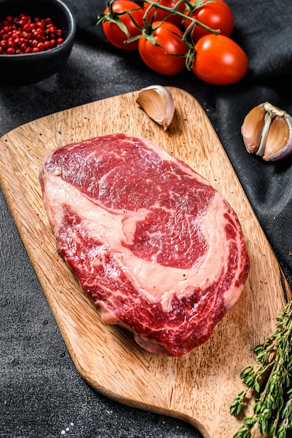 Bifteck de faux-filet de viande fraîche crue avec assaisonnement sur planche à découper