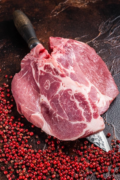 Bifteck de longe de porc à partir de viande de filet de cou crue sur un couteau de boucher Fond sombre Vue de dessus