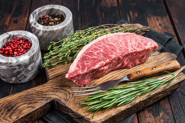 Bifteck de rumsteck ou de surlonge cru Wagyu A5, viande de bœuf de kobe sur une planche de boucherie. Fond en bois sombre. Vue de dessus.