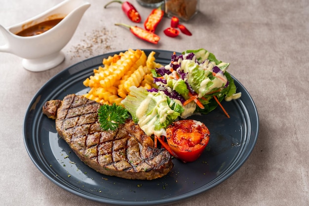 Bifteck de surlonge grillé avec frites et salades. Servir sur plaque noire. Espace négatif.