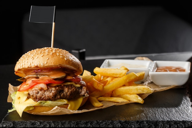 Big cheeseburger unique avec des frites isolé sur fond noir