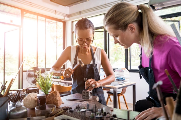 Bijoutier enseignant et étudiant fabriquent des bijoux en atelier