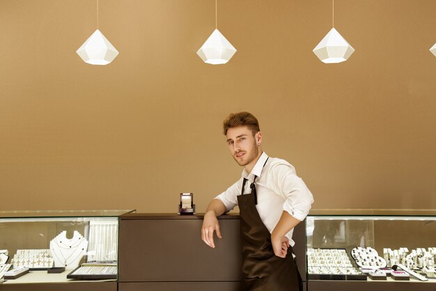 Bijoutier mâle se tient dans un magasin de bijoux