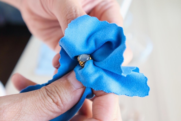 Bijoutier polissant et nettoyant à la main une bague de bijoux en or avec un tissu en microfibre