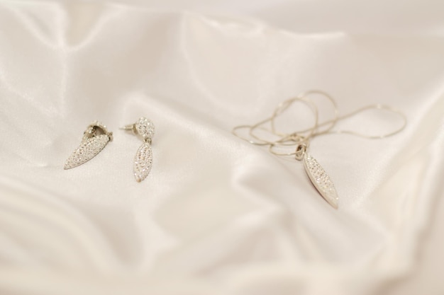 Bijoux fantaisie pour la mariée boucles d'oreilles et pendentif avec chaîne sur fond de soie blanche